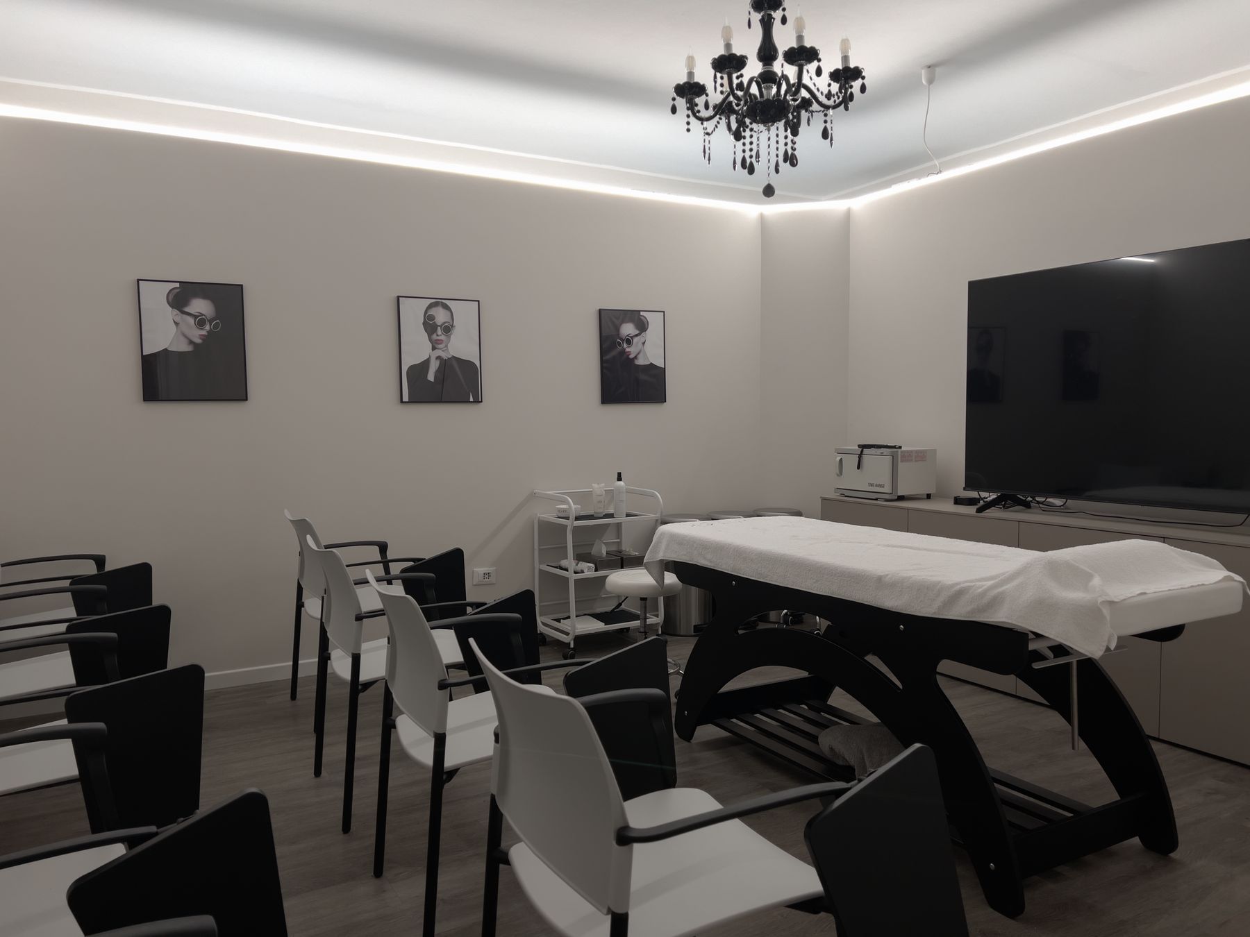 Sala dell'Académie con lampadario nero, maxischermo e lettino